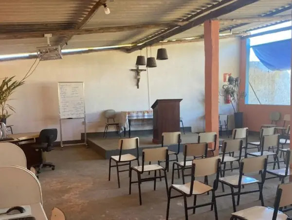 Salão coberto com cadeiras enfileiradas, púlpito e quadro branco